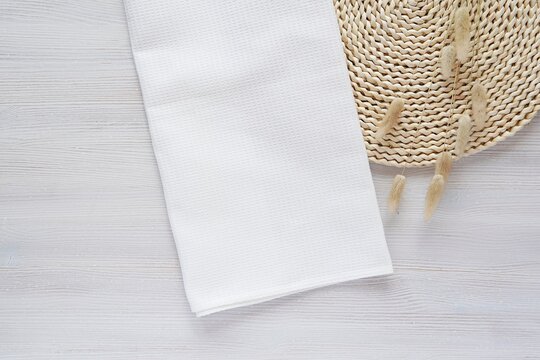 White waffle fabric kitchen towel mockup for design presentation, bohemian style composition with blank cotton towel and wicker mat.