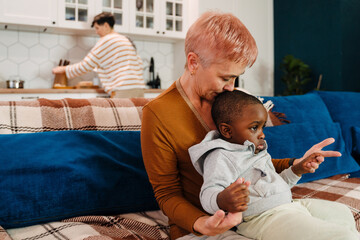 Mature woman playing with her adopted child while sitting on couch