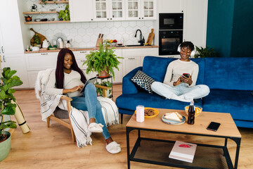 Young black women using gadgets while resting at home