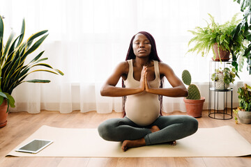 Black pregnant woman meditating during yoga practice