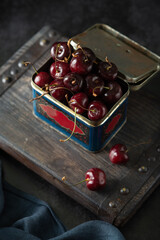 Fresh organic cherries in a tin box on a dark background. Close up - 622676229