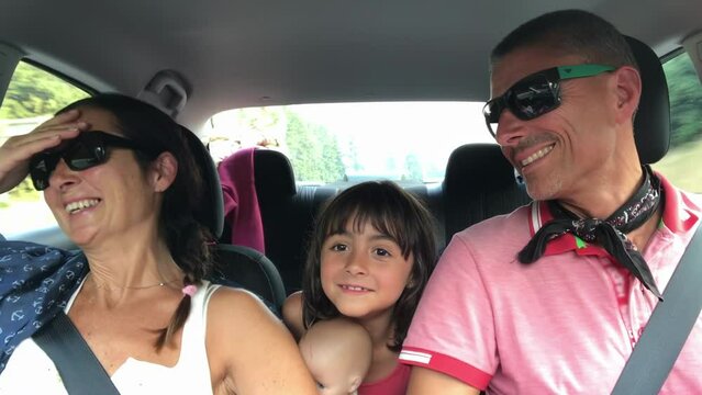 Cheerful young traditional family has a long auto journey. Summer Road Trip. Happy Caucasian Family Of Three Singing in the Car