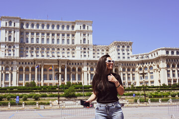   Bucharest ,Romania Constitution Square.  Young beautiful smiling  woman  using a mobile phone...