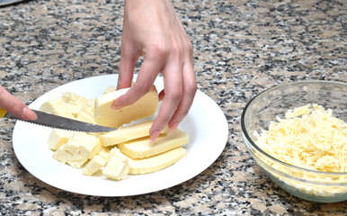 hands cutting and grating a piece of parmesan cheese