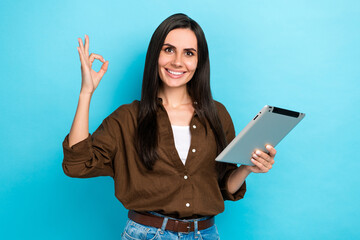 Photo of sweet shiny lady wear brown shirt showing okey gesture texting modern device isolated blue color background