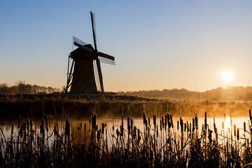 Dutch windmill by the water at sunrise