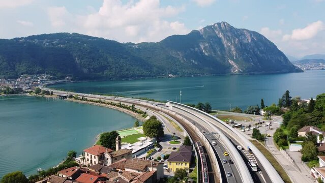 Melide, Switzerland: Aerial drone footage of a train on the bridge on lake Lugano between Bissone and Melide in Canton Ticino in the Swiss alps. 
