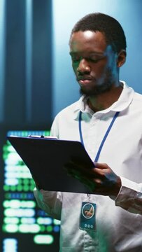 Vertical video African american engineer preventing supercomputer cybersecurity issues arising due to unsecured network connections. Specialist making sure data center is invulnerable to phishing
