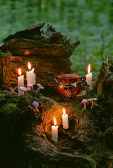 witch cauldron with amulet and burning candles in forest, abstract dark natural background. occult...