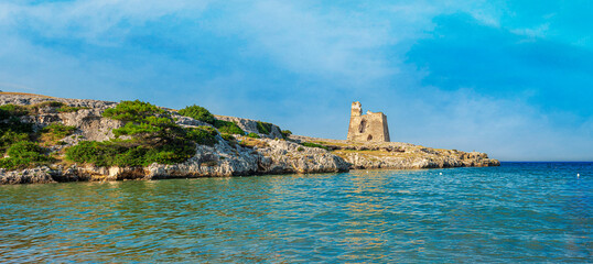 View of an ancient watchtower on a promontory of a beach in the natural park of Gargano, Puglia....