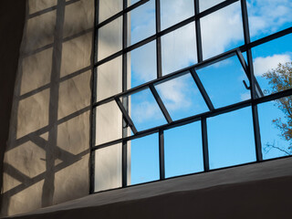 Close-up of a lattice window. Open for ventilation. Blue sky with clouds.