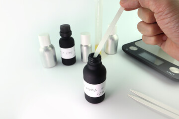 essential oil bottle , chemical beaker are on white table with blotting papers , fragrance bottle...