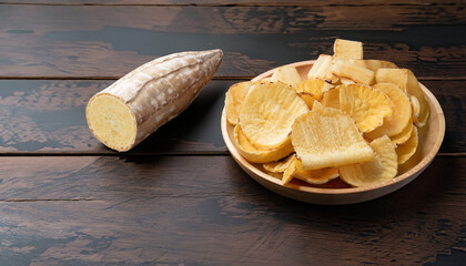 delicious cassava chips and some cassava on dark wood background with copy space
