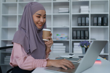 Portrait of a business woman using laptop computer and drinking coffee.