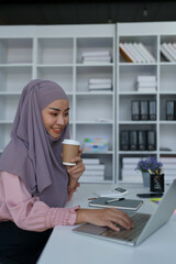 Portrait of a business woman using laptop computer and drinking coffee.