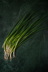 Green onions on the dark green background top view. Space for text - 622702467