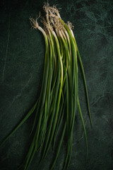 Green onions on the dark green background top view. Space for text - 622702490