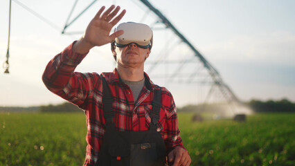 agriculture virtual reality. a farmer in virtual reality glasses controls a machine to irrigate...