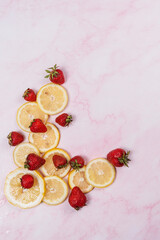 Obraz na płótnie Canvas strawberries and lemons on pink marble background
