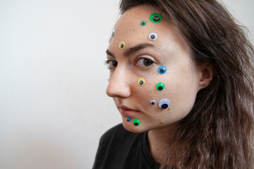 Young Ukrainian girl with white skin and dark hair with big eyes and stickers on her face emotionally depressed mental health issues portrait scared surprised emotions eyesight problems close-up skin 