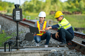 Architects and engineers point to railroad switches and use laptops to point out railway tracks that need to be accelerated in the railway switch construction process.