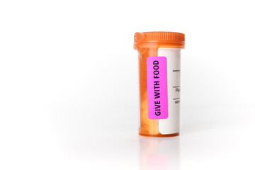 Pill bottle with Give with food lable. Orange prescription bottle for people, pets or animals. Child proof pill dispenser. For drug treatments, medication, supplements or vitamins. Selective focus.