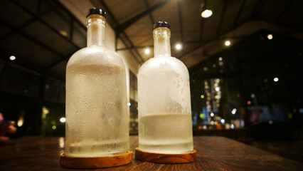 Selective focus, A clear glass bottle filled with cold water, clear glass bottle holds cold mineral...