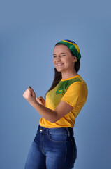 jovem brasileira sorridente  comemorando celebrando brasil campeão, cores verde e amarelo 