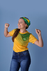 jovem brasileira sorridente  comemorando celebrando brasil campeão, cores verde e amarelo 