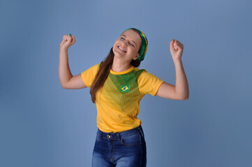 jovem brasileira sorridente  comemorando celebrando brasil campeão, cores verde e amarelo 