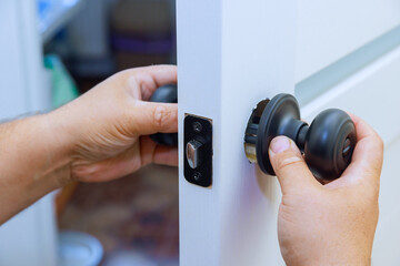 With aid of screwdriver worker affixes lock to freshly installed interior door.