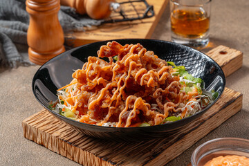 Crispy beef fillet pieces with mayonnaise plating on a black plate