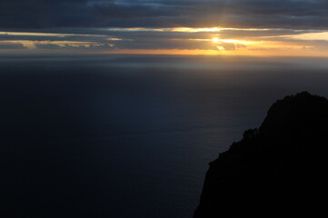 Beautiful sunset over ocean in golden hour with clouds and mountain  in summer