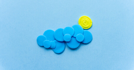 Plasticine sun with cloud. Modeling clay handmade weather on blue background.