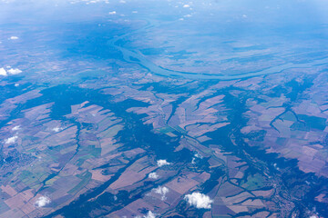 Naklejka na ściany i meble View to a land and clouds from airplane