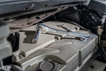Close up of ratchet and fix wrench sitting on car's engine