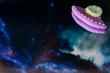 Alien spaceship UFO is flying at night. Clay hand made colorfull figures. Childrens fantasy about cosmos.