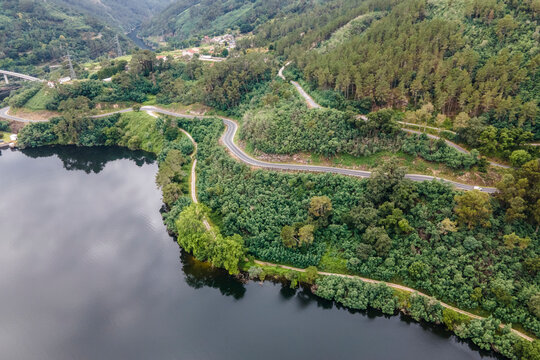 Aerial view of a road driving along the coast of Minho river in Val de Pereira, Ourense, Spain.