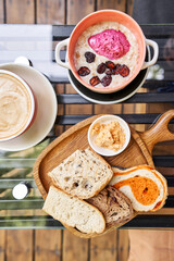 Breakfast with fresh cooked porridge served with Dry Cherry with strawberry sorbet in bowl. Assorted sliced bread on a wooden board. Served with smoked butter. Breakfast with cappuccino coffee.