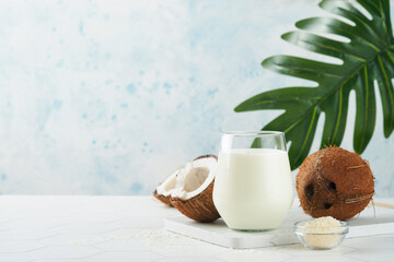 Glass of coconut milk and coconut close up on a white background with space for text. Coconut vegan milk non dairy or Dairy free milk concept. Healthy vegan food.