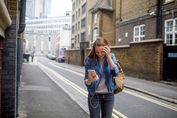 Young woman using a phone while walking in the city london