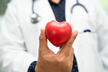 Doctor holding a red heart in hospital ward, healthy strong medical concept.