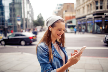 Fototapeta premium Young woman using a phone while walking in the city london