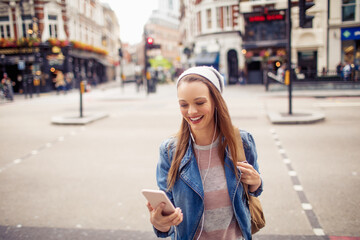 Fototapeta premium Young woman using a phone while walking in the city london
