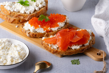 Sandwiches with red caviar, cottage cheese and salted salmon. Wooden cutting Board. Close up