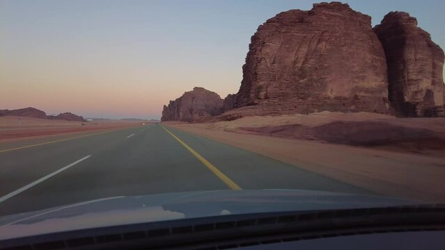 Tabuk, Saudi Arabia: Point of view of a car driving on the stunning red desert out of Tabuk in northwest Saudi Arabia in the middle east at sunset. 