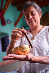 Mujer mayor haciendo terapia de cuenco tibetano
