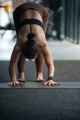 Fototapeta premium Woman stretches her body by doing a head bend and tapping the ground with her hands for a yoga pose, ready for yoga poses
