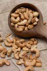 Roasted cashew nuts and halves in wooden bowl on table top view. Macro studio shot Homemade Roasted Salted Cashews in basket and spoon breakfast on sack, Healthy food Seeds snack product