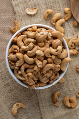 Roasted cashew nuts and halves in wooden bowl on table top view. Macro studio shot Homemade Roasted Salted Cashews in basket and spoon breakfast on sack, Healthy food Seeds snack product